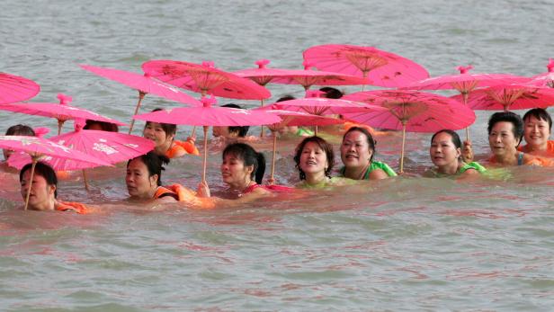 Winter swimmers hold umbrellas whilst swimming in Yong River in Nanning