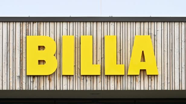 Große gelbe Buchstaben mit dem Schriftzug „BILLA“ an einer Fassade aus senkrechten Holzlatten.