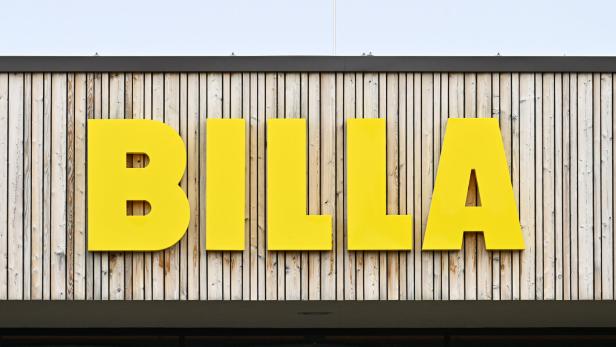Große gelbe Buchstaben mit dem Schriftzug BILLA an einer Fassade aus senkrechten Holzlatten.