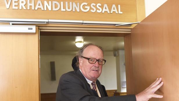 Ein Mann mit Brille steht im Eingang eines Verhandlungssaals.
