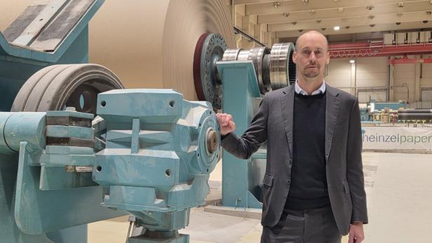 Mann im Anzug steht in einer Produktionshalle