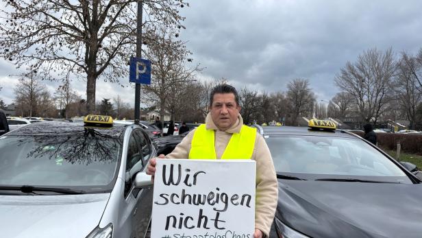 Mann mit Schild vor Autos