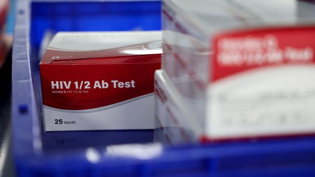 Eine Packung HIV-Antikörpertests mit rotem und weißem Design steht in einer blauen Kiste.