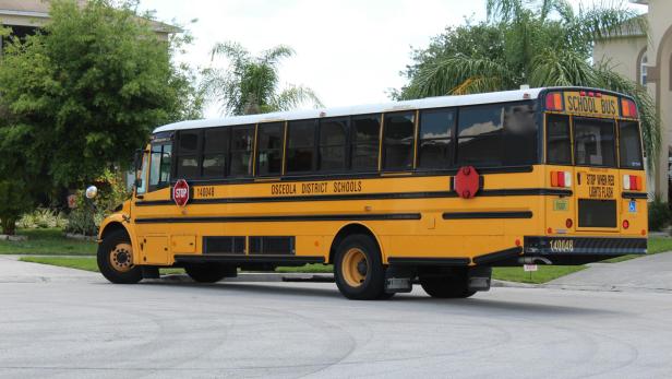 Ein gelber Schulbus steht an einer Straßenecke.