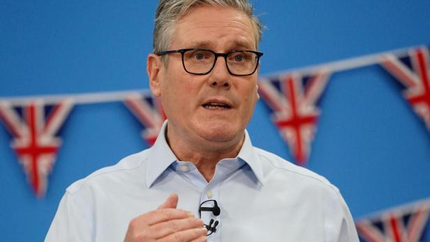Keir Starmer spricht vor einem blauen Hintergrund mit Union-Jack-Girlanden.
