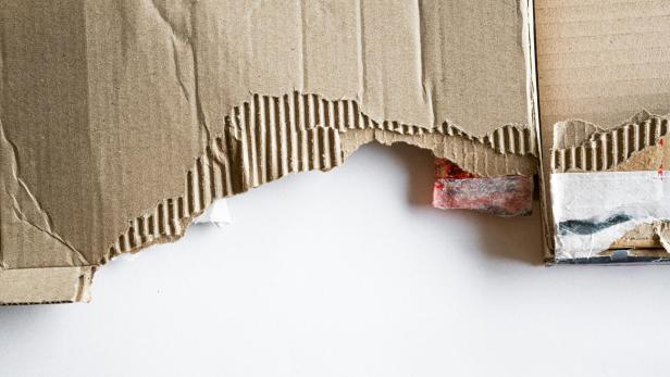 Zerrissene Wellpappe liegt auf einer weißen Oberfläche.