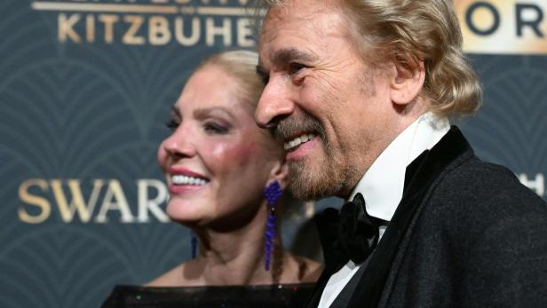Thomas Gottschalk und eine Frau lächeln vor dem Hintergrund des Filmfestivals Kitzbühel.