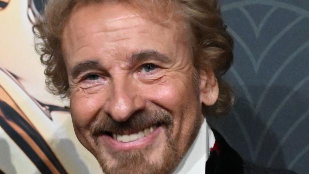 Nahaufnahme von Thomas Gottschalk mit Fliege und dunklem Jackett vor gemustertem Hintergrund.