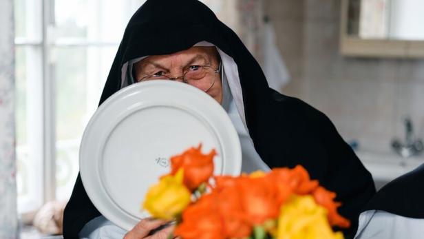 Eine Ordensfrau lugt hinter einem weißen Teller hervor.