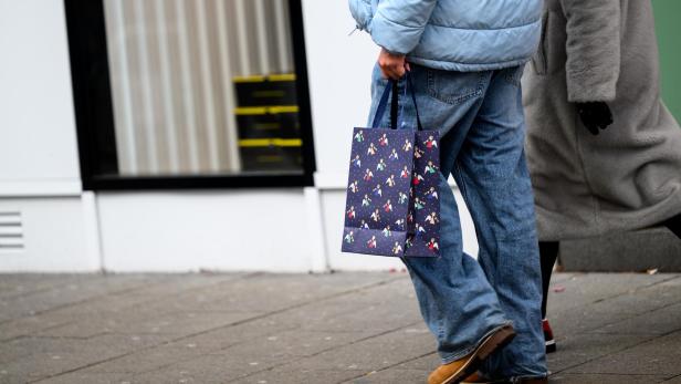 Mensch mit Geschenkstüte geht auf der Straße