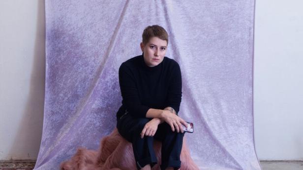 Die Künstlerin Käthe Löffelmann sitzt vor einem ihrer Kunstwerke.