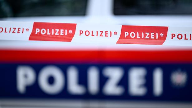 Zwei rot-weiße und blau-weiße Absperrbänder mit der Aufschrift "Polizei" sind zu sehen.