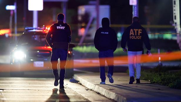 Drei Polizisten, darunter einer vom Sheriff S.T.A.C. und einer von der ATF, gehen nachts auf dem Bürgersteig.