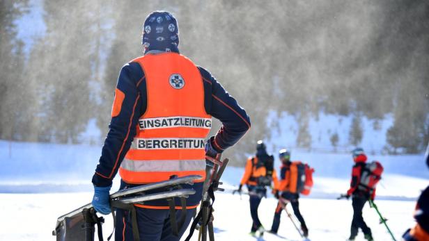 Mehrere Bergretter mit orangefarbenen Warnwesten