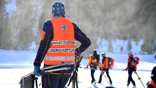 Mehrere Bergretter mit orangefarbenen Warnwesten