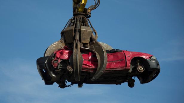 Autowrack wird von großem Greifarm/Kran hochgehoben.