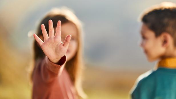 Ein Kind hält die offene Handfläche nach vorne, während ein weiteres Kind daneben steht.