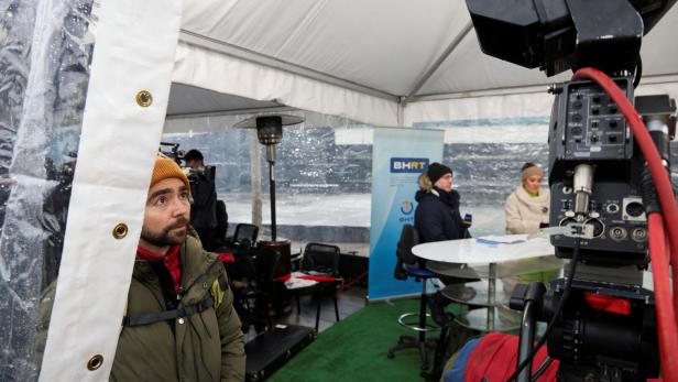 Ein Mann mit Mütze schaut in ein Zelt, wo ein Interview für BHRT gefilmt wird.