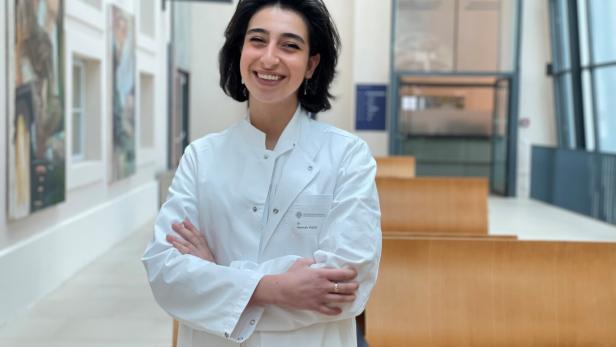 Hannah  Vizaei steht in einem langen hellen Gang der Wiener Zahnklinik.