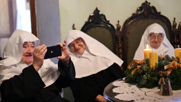 Drei Nonnen, eine hält ein Smartphone 