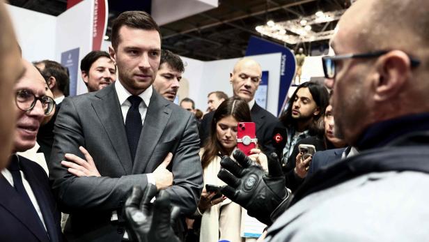 Ein Mann steht mit verschränkten Armen vor anderen Menschen