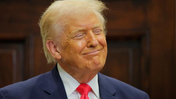 Donald Trump lächelt mit geschlossenen Augen in einem dunklen Anzug und roter Krawatte.