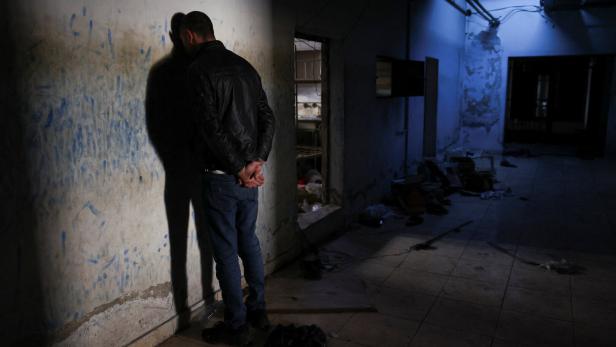 Former Syrian detainee in the Palestine Branch, Motasem Kattan, re-enacts inside a prison cell where he was detained in Damascus, Syria