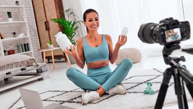 Eine Influencerin sitzt vor einer Videokamera und bewirbt Nahrungsergänzungsmittel.