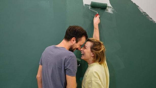 Junges Paar malt die Wände der neuen Wohnung grün aus.  