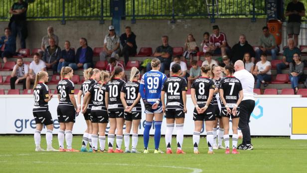 Spielerinnen des LASK stehen auf einem Fußballplatz und sind von hinten zu sehen