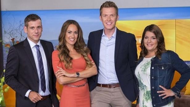 Vier Personen posieren vor einem gemalten Hintergrund für ein Gruppenfoto.