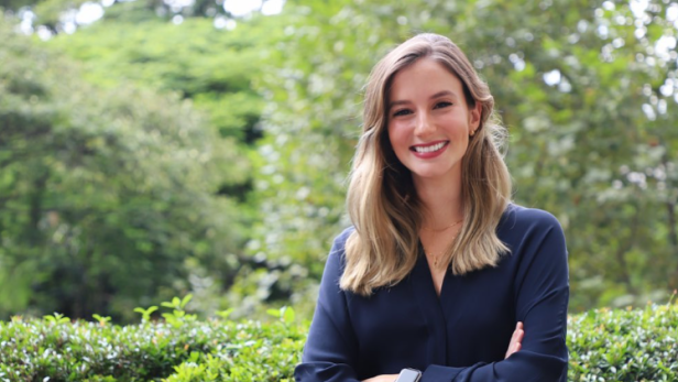 Luana Lopes Lara im Porträt-Format vor Garten.