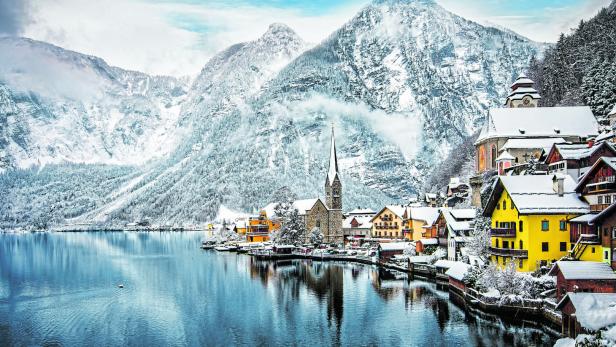 Winterliches Hallstatt mit schneebedeckten Bergen und Häusern am See.