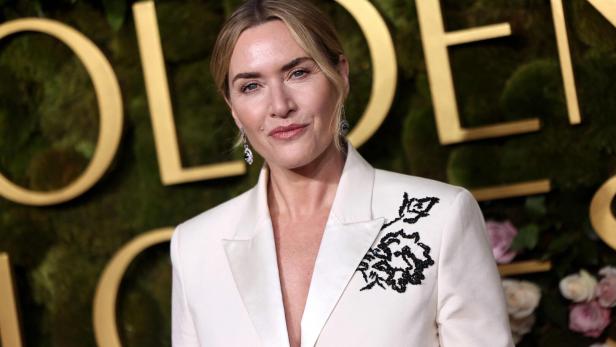 Kate Winslet trägt einen weißen Blazer mit schwarzer Blumenapplikation.