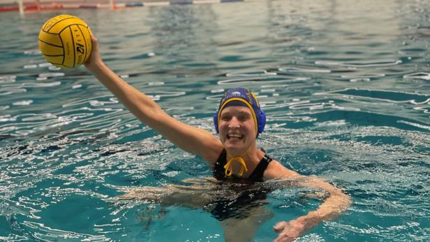 Anna Hofbauer hält im Wasser mit ihrer Rechten einen gelben Ball in die Höhe.