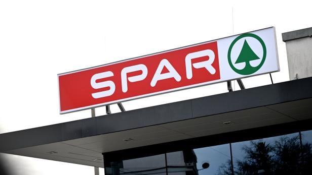 Ein rotes SPAR-Logo mit weißer Schrift und grünem Tannenbaum-Symbol auf einem Geschäftsdach.