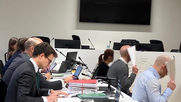 Angeklagte und Anwälte in einem Gerichtssaal.