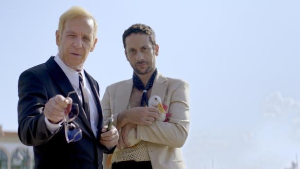 Zwei Männer, von denen einer eine Gans hält.