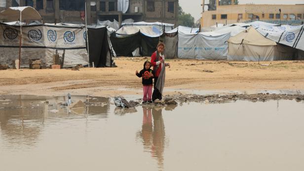 Displaced Palestinians shelter in a tent camp on a rainy day in Khan Younis