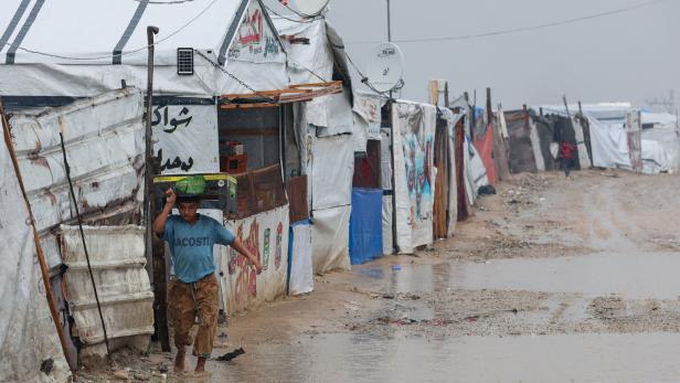 Displaced Palestinians shelter in a tent camp on a rainy day in Khan Younis