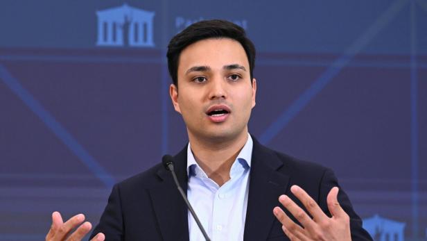 Ein Mann im Anzug, es ist Neos-Klubobmann Shetty, spricht gestikulierend an einem Mikrofon, vor ihm steht ein Glas Wasser.