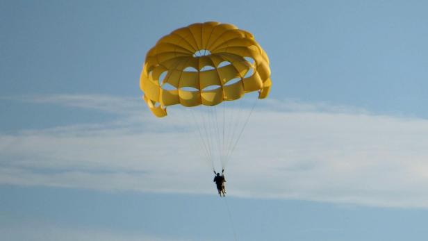 Flugzeugspringer mit gelbem Fallschirm im Himmel