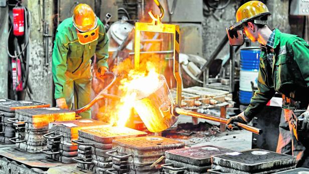 Group of workers in a foundry at the melting furnace - production of steel castings in an industrial company