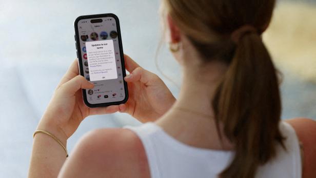 FILE PHOTO: A teenager poses holding a mobile phone displaying a message from TikTok in Sydney