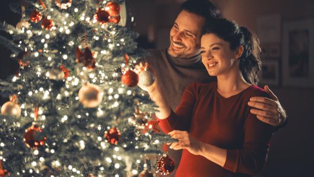 A loving happy young adult couple celebrating Christmas and decorating the Christmas tree