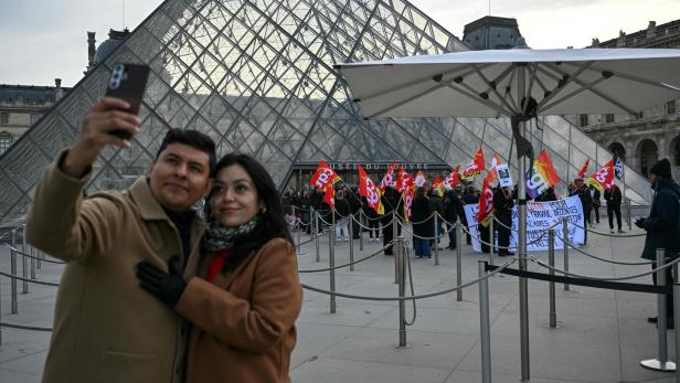 Ein Paar macht ein Selfie vor der Glaspyramide des Louvre