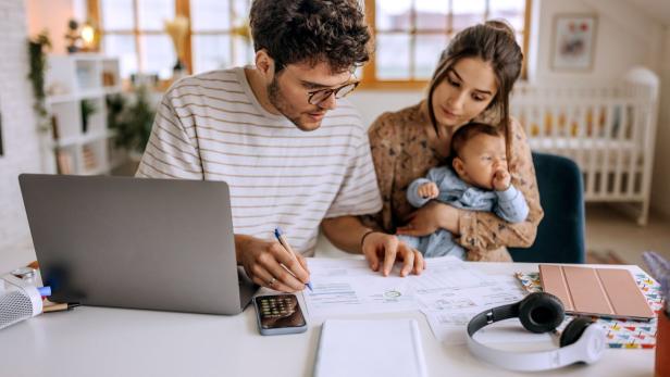 Young family with cute little baby boy going over finances at home