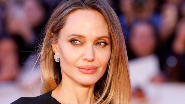 Angelina Jolie mit blondem Haar und Ohrringen blickt zur Seite.