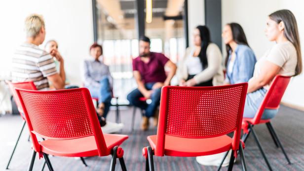 Eigentümerversammlung in einem Wohnhaus auf roten Stühlen