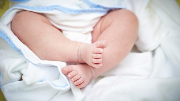 Babyfüße in einem Bett.